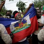 Protesters gesture in front of Haitian National Police (PNH) officers at a police cordon during a march to demand the resignation of Haitian President Jovenel Moise, in the streets of Petion Ville, Port-au-Prince