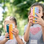 little-girls-use-phones-in-trendy-cases-for-anti-stress-pop-it-1