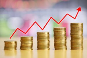 109846607-pila-de-monedas-de-oro-del-concepto-de-crecimiento-financiero-y-flechas-rojas-se-elevan-en-el-suelo