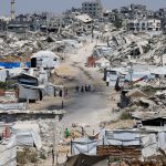 People walk at a site destroyed during the Israeli offensive, in Beit Lahiya