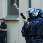 Un policía antidisturbios dispara un arma durante una manifestación estudiantil en Lyon, Francia.